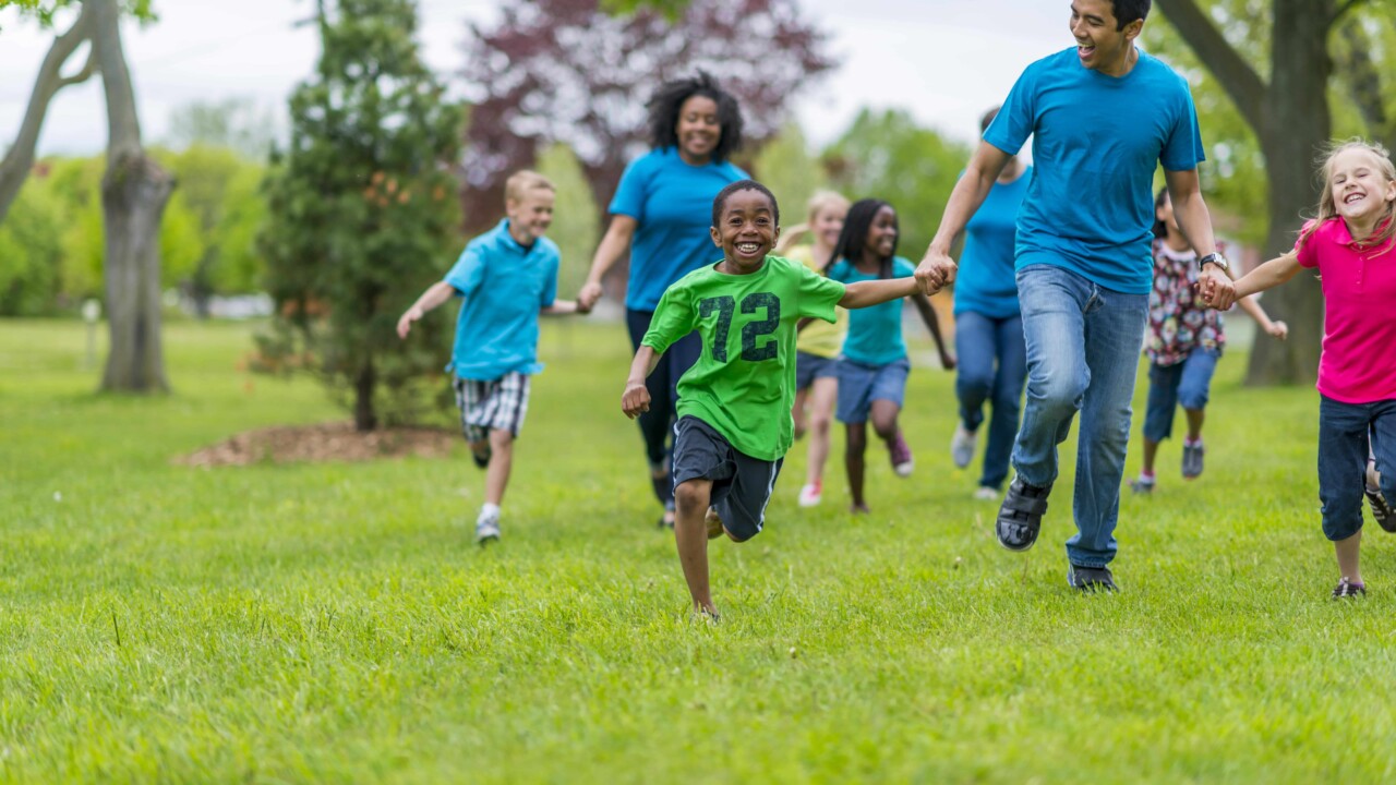 Adults and kids holding hands and racing.